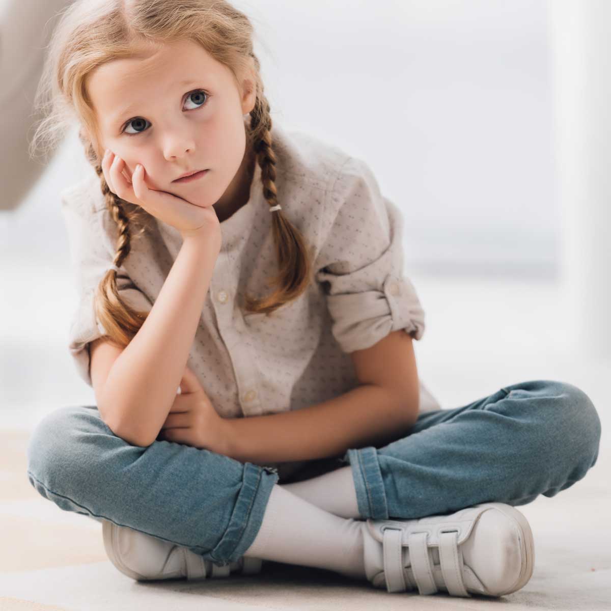 Young child sitting with her legs crossed looking anxious