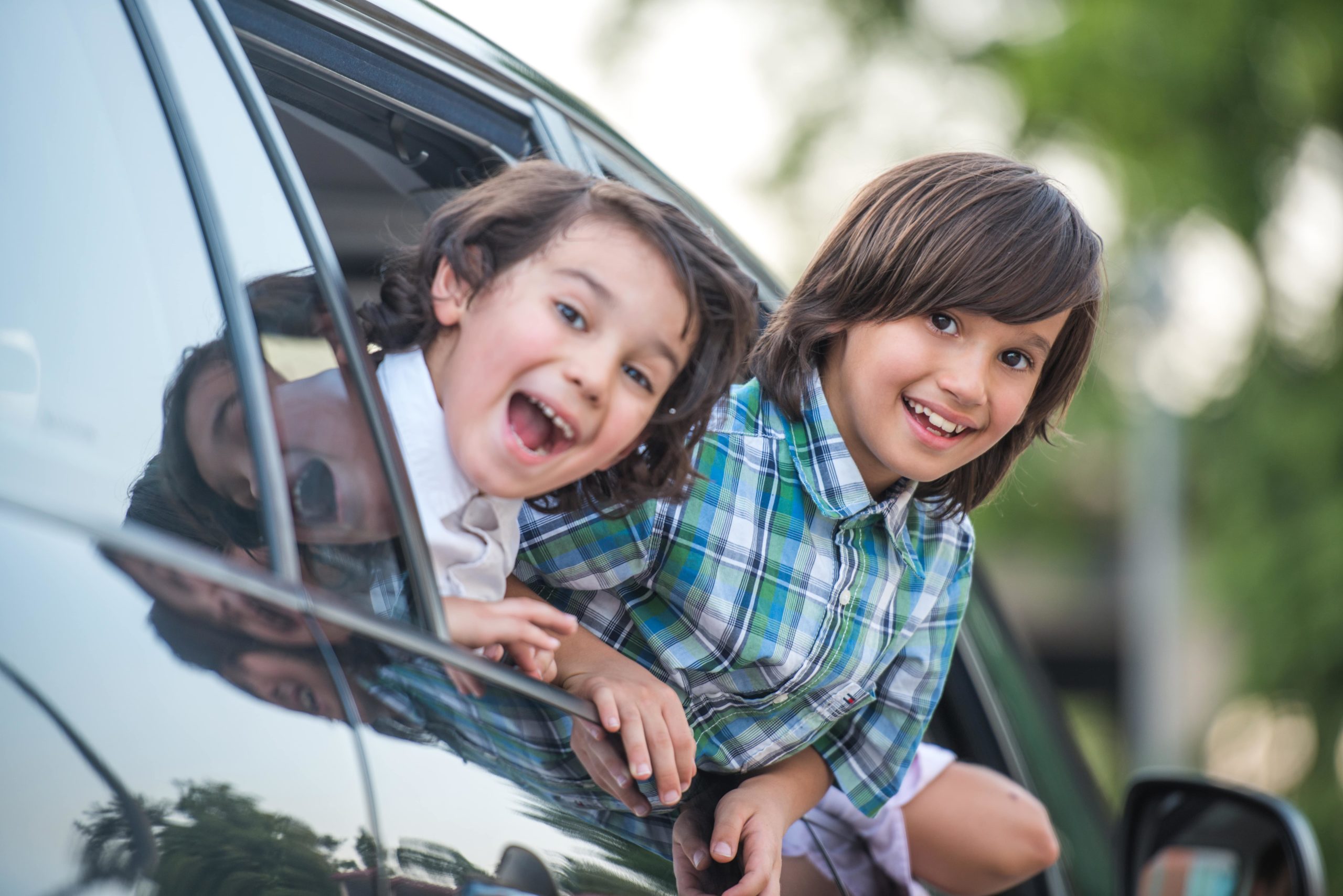 Two kids leaning out of a car window